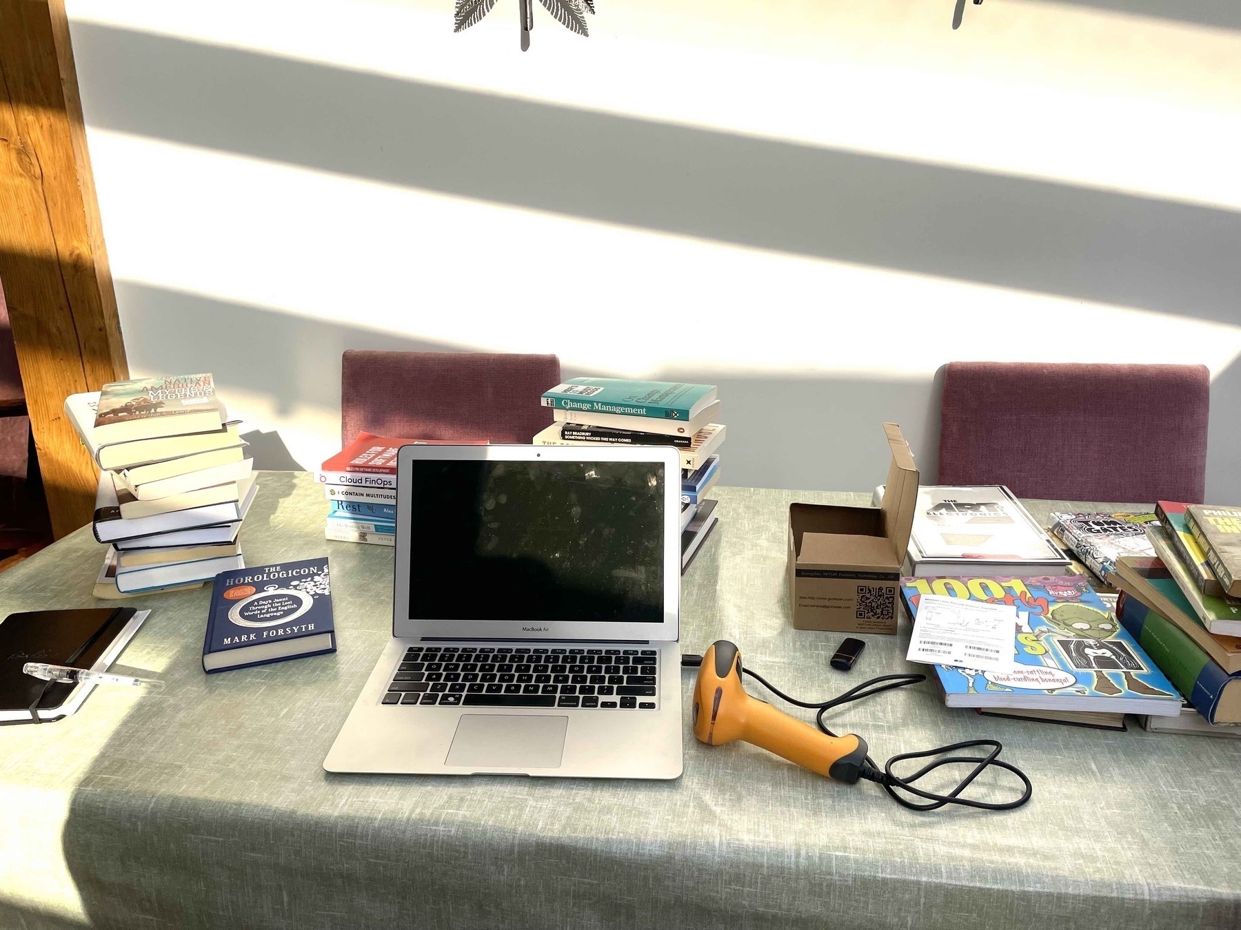 Stacks of books, a computer and a barcode scanner on a table